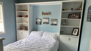A bedroom with a bed, built-in shelving, and a wall-mounted decoration. - 3 blocks from Taylors Creek, 1 mile from Beaufort waterfront and boat ramp (Beaufort)