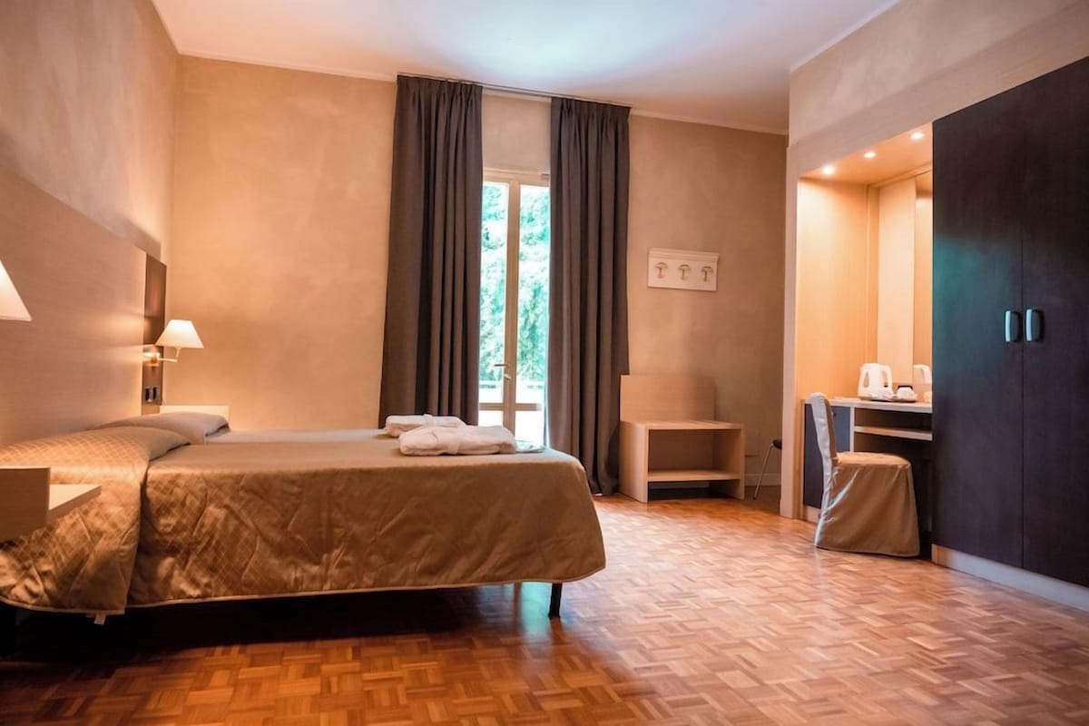 Une chambre d’hôtel avec un lit, un bureau, une chaise et une armoire.