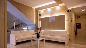 Un hall d’entrée moderne avec un canapé blanc, une table basse et un escalier en arrière-plan.