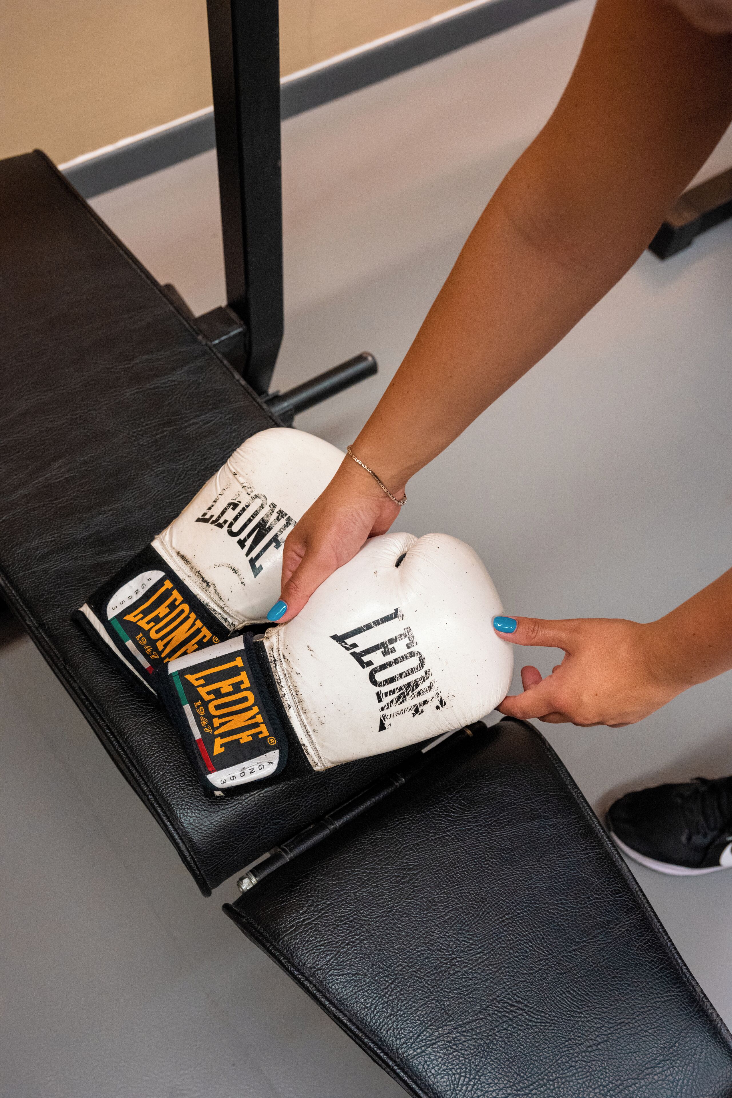 Una persona colocando guantes de boxeo en un banco.