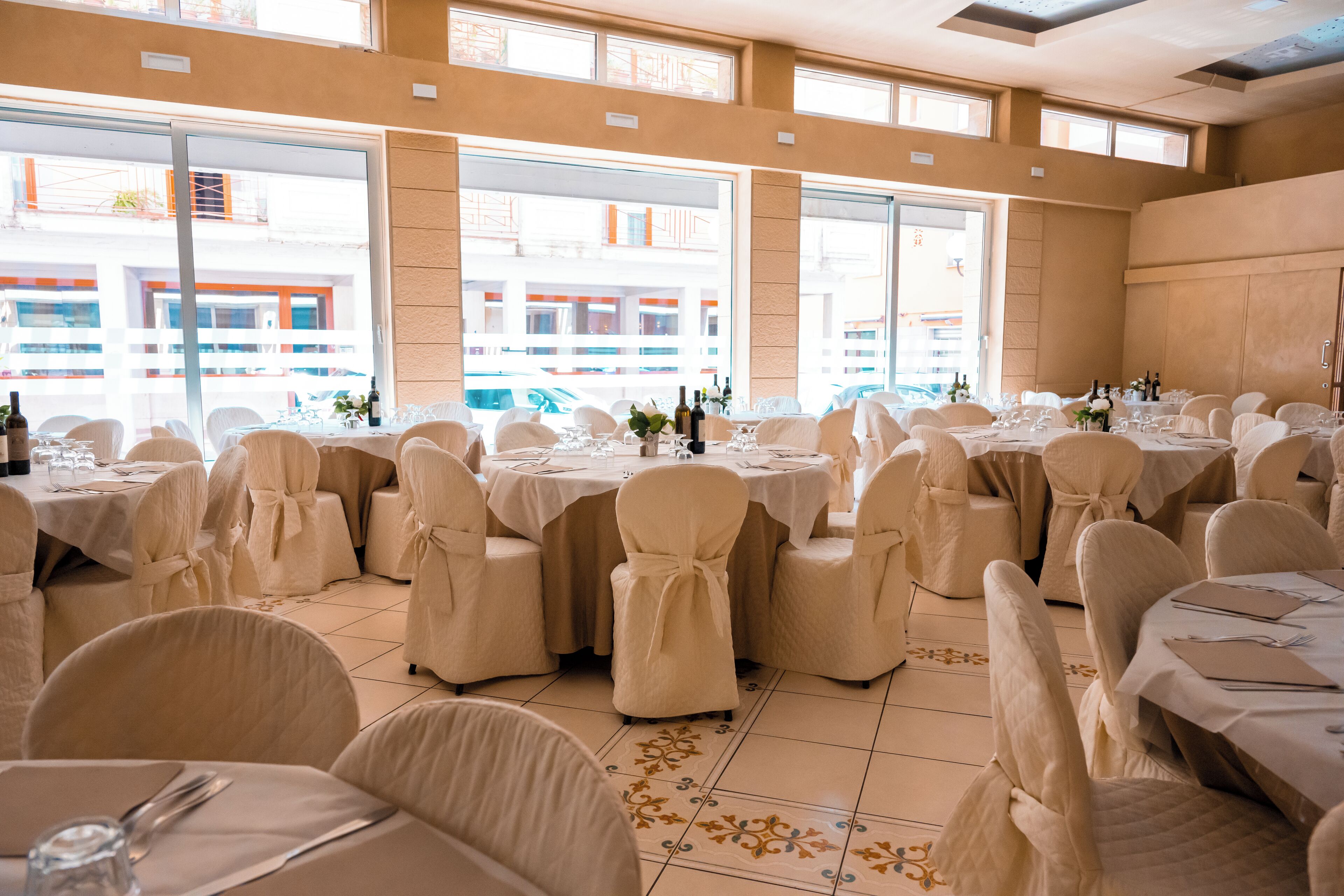 Une salle de banquet avec des tables rondes, des chaises et un sol carrelé.