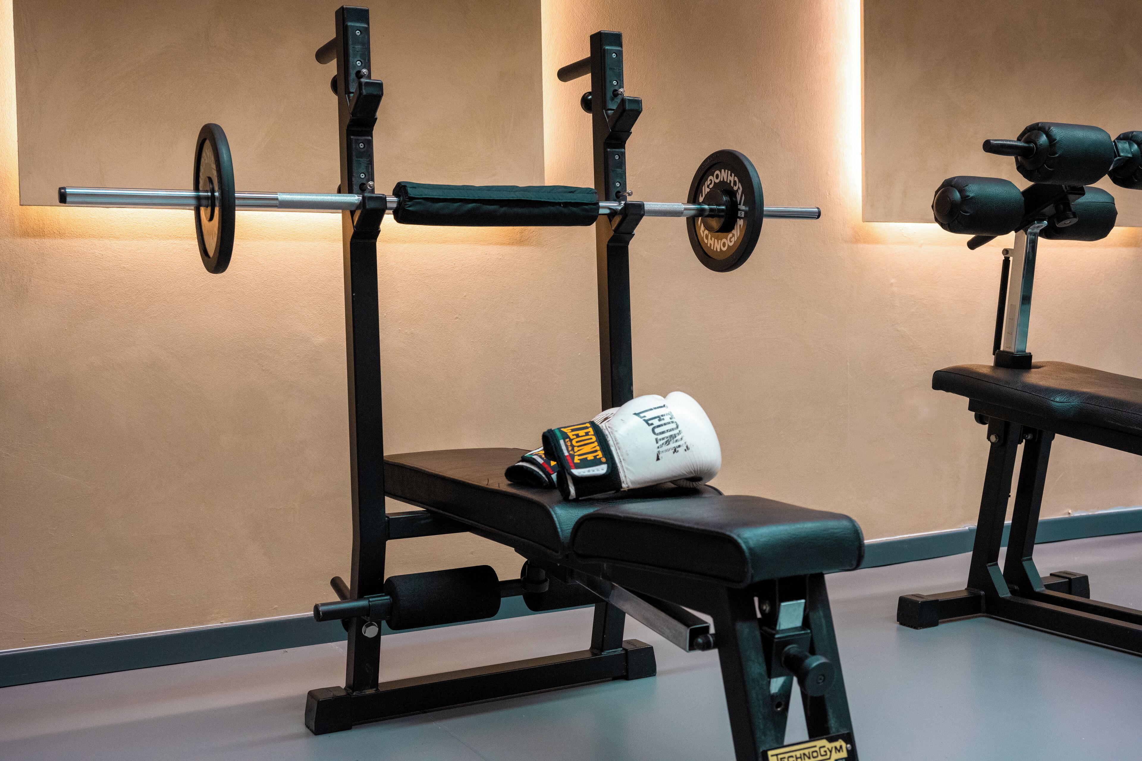 Un gimnasio con equipo de levantamiento de pesas, una banca y guantes de boxeo.