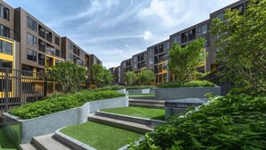 A modern apartment complex with multiple buildings, green landscaping, and a clear sky. - The Base Central Phuket- 6 Floor (Wichit)