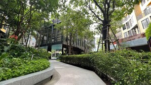 A pathway flanked by lush greenery and modern buildings with balconies. - The Base Central Phuket- 6 Floor (Wichit)