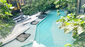 A swimming pool with multiple lounge areas and surrounding greenery. - The Base Central Phuket- 6 Floor (Wichit)