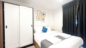 A hotel room with a double bed, a wardrobe, a bedside table with a lamp, and four framed pictures on the wall. - The Base Central Phuket- 6 Floor (Wichit)