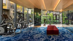A gym with exercise equipment and a red bench, large windows, and a blue patterned carpet. - The Base Central Phuket- 6 Floor (Wichit)