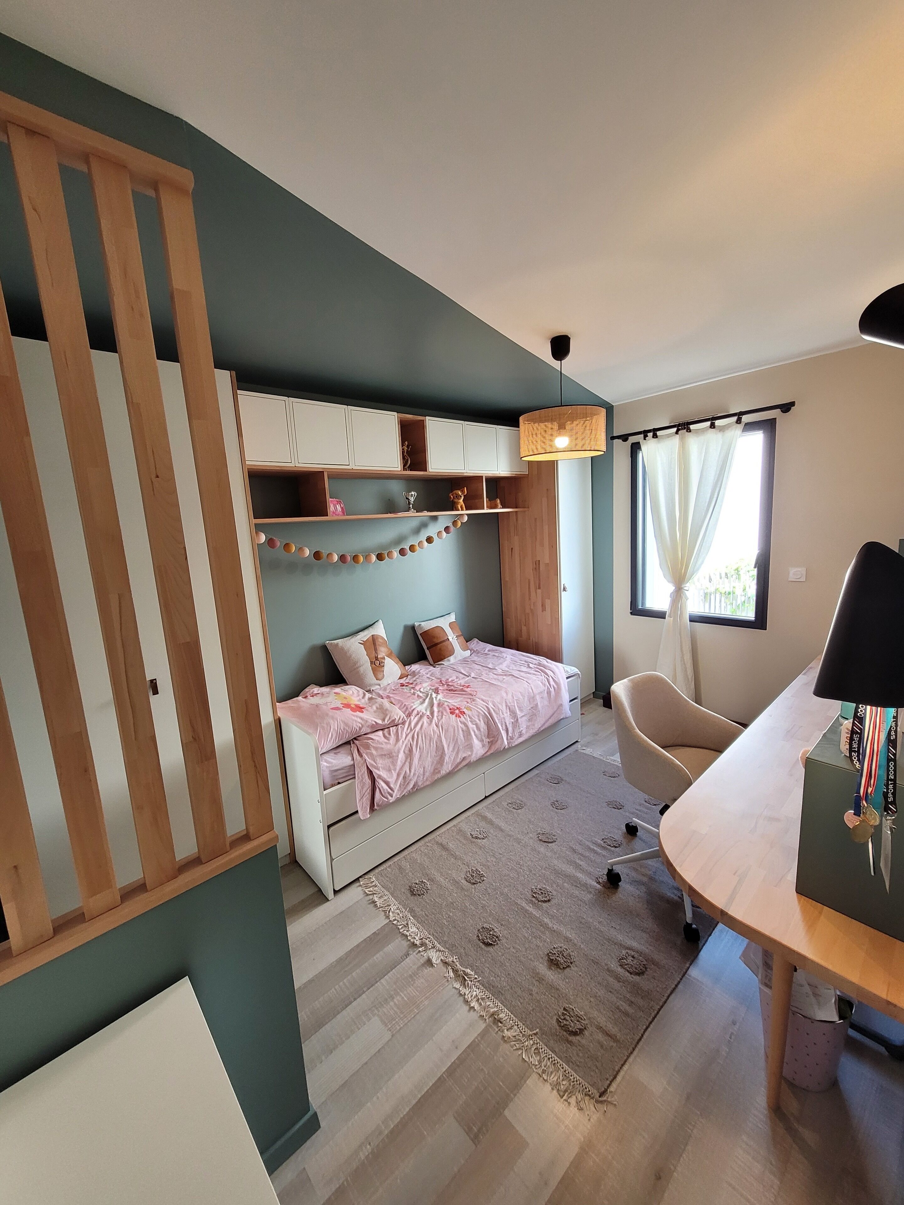 Une chambre à coucher avec un lit, un bureau, une chaise et une fenêtre avec des rideaux.