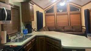 Una cocina con armarios de madera, microondas, estufa y lavamanos.