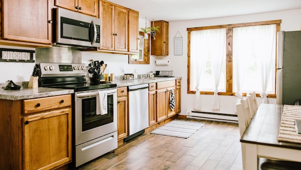 A kitchen with wooden cabinets, stainless steel appliances, and a large window with curtains. - Come Visit “Mint To Be”
 (Somerset)