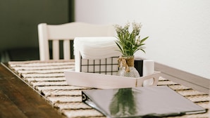 A dining table with a white tablecloth, a potted plant, and a black notebook. - Come Visit “Mint To Be”
 (Somerset)