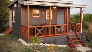 Ein kleines, eingeschossiges Haus mit Veranda, Eingangstür und einem kleinen Fenster.