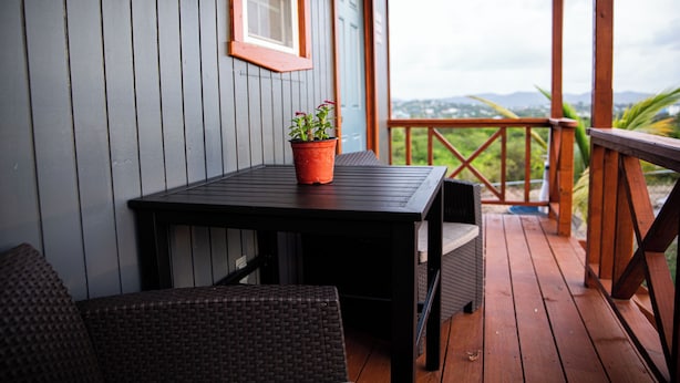 Eine Holzterrasse mit Tisch und Stühlen, einem Blumentopf und Blick auf die Landschaft.