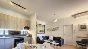 A modern kitchen with a built-in oven and microwave, a dining area with a round table set for breakfast, and a living area with a sofa and coffee table. - N&J - MADAGASCAR - Central - Very close sea (Niza)