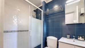A bathroom with a glass shower enclosure, a toilet, and a sink with toiletries. - N&J - TERRACOTTA- Central - Proche mer (Niza)