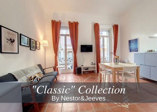 A modern living room with a sofa, a dining table, and a TV mounted on the wall. - N&J - TERRACOTTA- Central - Proche mer (Niza)