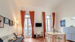 A modern living room with a sofa, a dining table, and a TV mounted on the wall. - N&J - TERRACOTTA- Central - Proche mer (Niza)