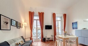 Un salon moderne avec un canapé, une table à manger et un téléviseur fixé au mur.