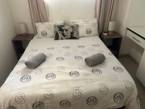 Un lit bien fait, avec une couvre-lit à motifs, deux oreillers et deux serviettes enroulées.