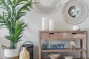 A wooden console table with a 'BE HAPPY' sign, surrounded by decorative items and wall art.