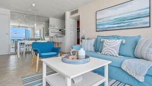 Un soggiorno moderno con un divano blu, un tavolino da caffè bianco e un'area pranzo con una sedia blu.