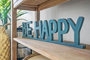 A wooden shelf with a decorative sign that reads "BE HAPPY".
