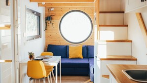 A compact kitchen with a dining area, a round window, and a staircase. - Transylvanian Tiny House Apuseni Mountains. (Mătișești, Comuna Horea)