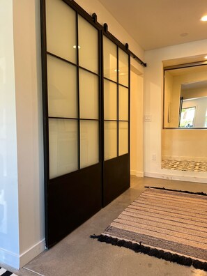 Contemporary space with a sliding glass door leading to a room, featuring a patterned rug and clean lines.