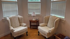A room with three upholstered armchairs, a small wooden table with a lamp, and a wicker basket. - The Victorian @ Lake Cumberland - Beaver Creek, firepit, sleeps 18 (Monticello)