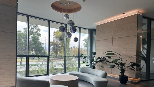Um lobby moderno com grandes janelas, um sofá curvo, uma mesa de centro redonda e um lustre.