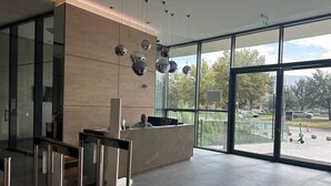 Uma área de recepção moderna com balcão, divisórias de vidro e vista para o estacionamento.