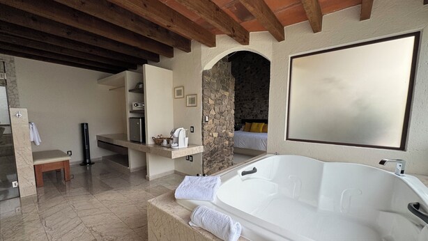 A modern bathroom with a large bathtub, marble flooring, and a stone archway.