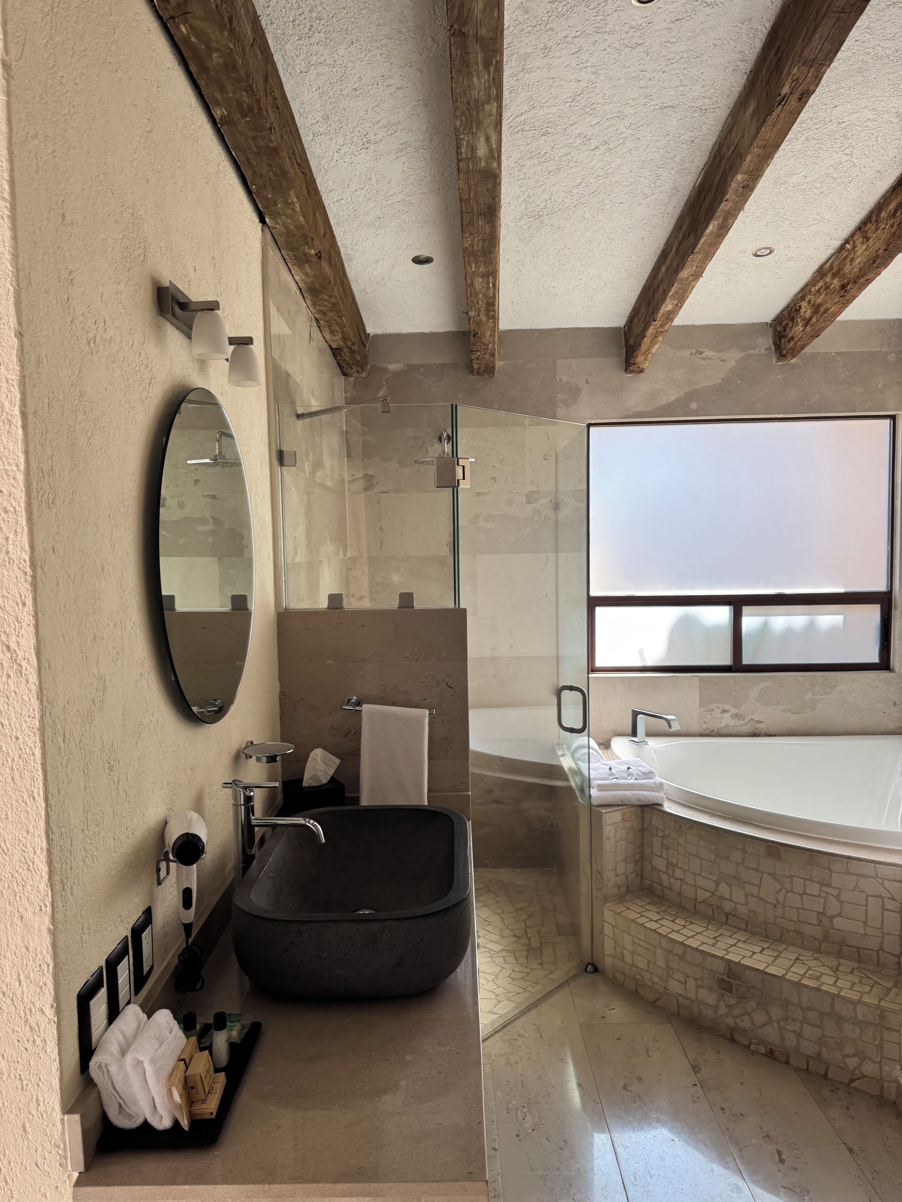 A modern bathroom with a large bathtub, a glass-enclosed shower, and a vanity with a mirror and towel rack.