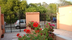Ein Balkon mit Blumenkasten, einem Metallgitter und einem parkenden Auto im Hintergrund.