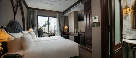 Ein Hotelzimmer mit einem großen Bett, einem Schreibtisch, einem Sessel, einem Fernseher und einem Badezimmer mit Spiegel und Waschbecken.