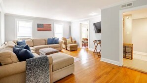 A spacious living room with a beige sofa set, a coffee table, and a TV mounted on the wall. - 4BR Creekside Country Hideaway on 34 Acres - Pet Friendly (Middlebrook)