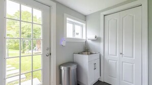 A clean, modern bathroom with a white vanity, a trash can, and a window providing natural light. - 4BR Creekside Country Hideaway on 34 Acres - Pet Friendly (Middlebrook)