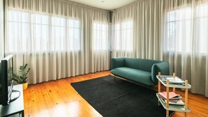 Ein Wohnzimmer mit einem grünen Sofa, einem schwarzen Teppich und einem kleinen Holztisch mit Büchern.