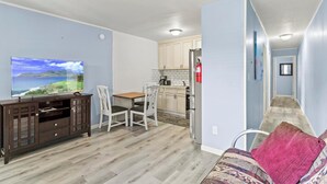 Un espacio habitable compacto con comedor, kitchenette y televisor que muestra una vista panorámica.