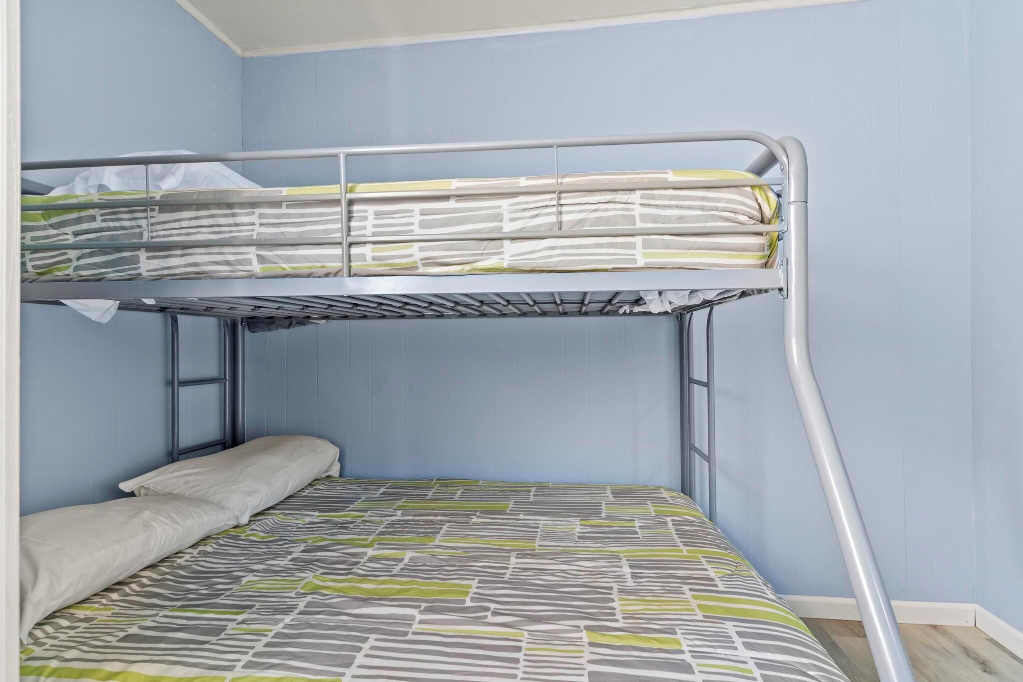A bunk bed with a metal frame and a patterned bedspread.