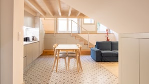 Une cuisine compacte comprenant un coin repas, un escalier et un canapé.