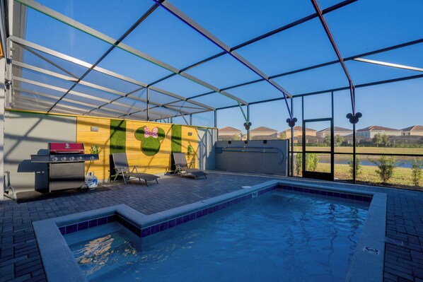 Relax by the pool with a clear view of the surrounding landscape, featuring a barbecue grill and comfortable lounge chairs.