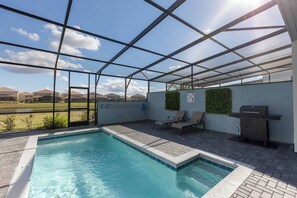 Un espace piscine avec vue sur le paysage, un barbecue et des chaises longues.