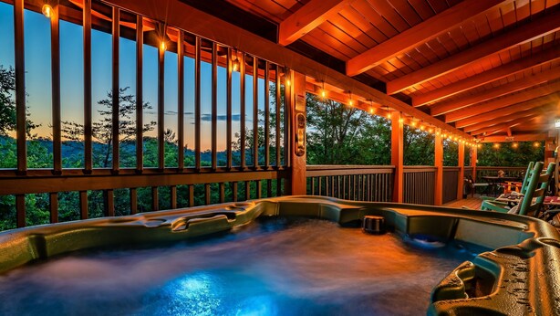 Ein Whirlpoolbereich mit Blick auf den Sonnenuntergang, eine Holzterrasse und Lichterketten.