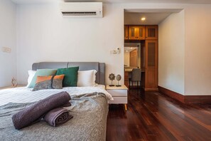 A neatly made bed with a gray headboard, a bedside table with decorative items, and a wooden cabinet in the background. - 30Pax 5BR Luxurious 57ft Pool KL  (Kuala Lumpur)