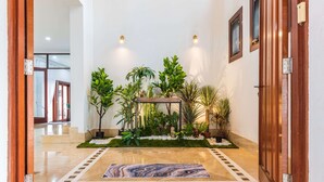 A hallway with a marble floor, a wooden door frame, and a potted plant arrangement. - 30Pax 5BR Luxurious 57ft Pool KL  (Kuala Lumpur)