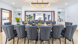 A modern dining area with a large round table, six grey chairs, and a chandelier. - 30Pax 5BR Luxurious 57ft Pool KL  (Kuala Lumpur)