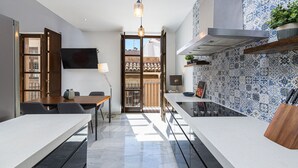 Una cocina moderna con salpicadero de azulejos, un comedor con mesa y sillas, y un ventanal con vistas a edificios.