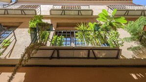 Un edificio con varios balcones, ventanas amplias y plantas en macetas.