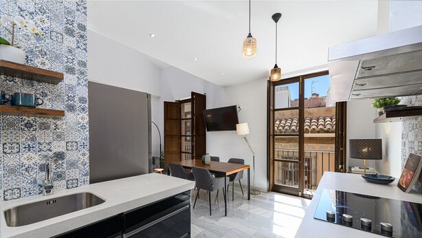 Una cocina moderna con una isla grande, electrodomésticos integrados y una zona de comedor con vistas.